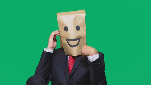 Koncepcja emocje, gesty. człowiek z torby papierowe na głowie, malowane emotikon, uśmiech, radość. rozmowy na telefon komórkowy — Zdjęcie stockowe