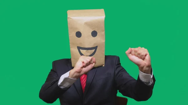 Concepto de emociones, gestos. un hombre con bolsas de papel en la cabeza, con un emoticono pintado, sonrisa, alegría — Foto de Stock