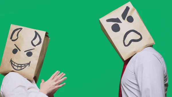 concept of emotions, gestures. a man with a package on his head, with a painted emoticon, one angry screaming, another crafty, and the devil laughs. trolling, lies, provocation