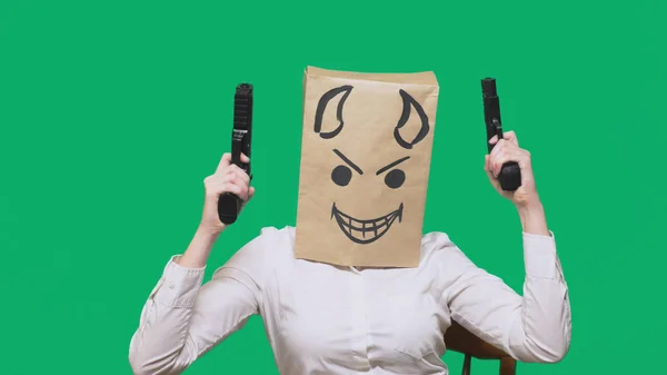 Conceptul de emoție, gesturi. un om cu un pachet pe cap, cu un zâmbet pictat furios, viclean, gloating, diavol, pistoale în mâini — Fotografie, imagine de stoc