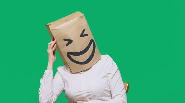 Concept d'émotions, de gestes. un homme avec des sacs en papier sur la tête, avec un émoticône peint, sourire, joie. parler sur un téléphone portable — Photo