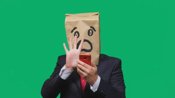 Conceito de emoções, gestos. um homem com sacos de papel na cabeça, com um emoticon pintado, medo. falando em um telefone celular — Fotografia de Stock