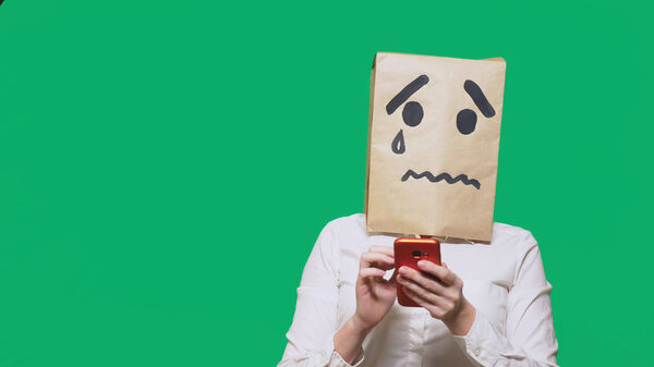 concept of emotion, gestures. a man with a package on his head, with a painted smiley crying, sad, talking on the phone