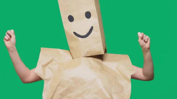 แนวคิดเรื่องอารมณ์ ท่าทาง ชายที่มีถุงกระดาษอยู่บนศีรษะ มีอีโมติคอนสี ยิ้ม ความสุข — ภาพถ่ายสต็อก
