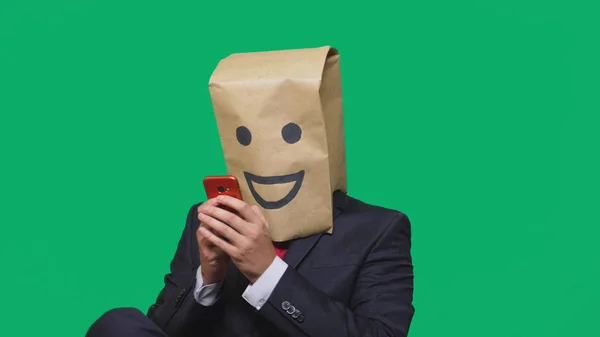 Koncepcja emocje, gesty. człowiek z torby papierowe na głowie, malowane emotikon, uśmiech, radość. rozmowy na telefon komórkowy — Zdjęcie stockowe
