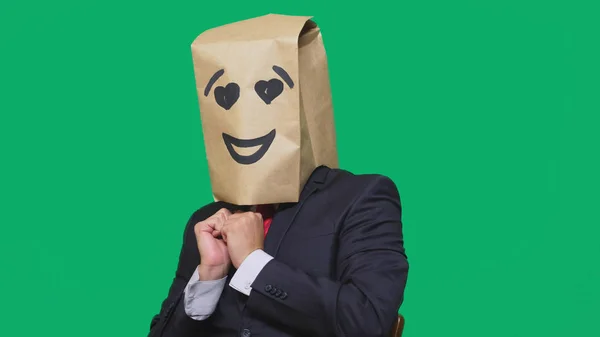 Concepto de emociones, gestos. un hombre con bolsas de papel en la cabeza, con un emoticono pintado, sonrisa, alegría, ojos de amor . —  Fotos de Stock