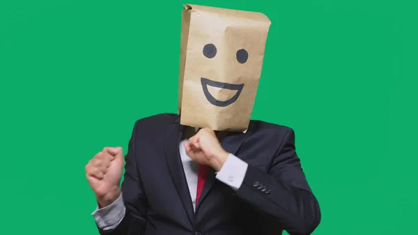 Concepto de emociones, gestos. un hombre con bolsas de papel en la cabeza, con un emoticono pintado, sonrisa, alegría — Foto de Stock