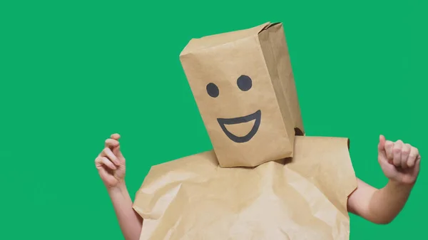 Concept d'émotions, de gestes. un homme avec des sacs en papier sur la tête, avec un émoticône peint, sourire, joie — Photo