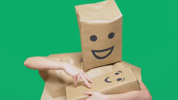 Concept of emotions, gestures. man with a package on his head, with a painted emoticon, smile, joy, laughter. plays with the child painted on the box. — Stock Photo, Image