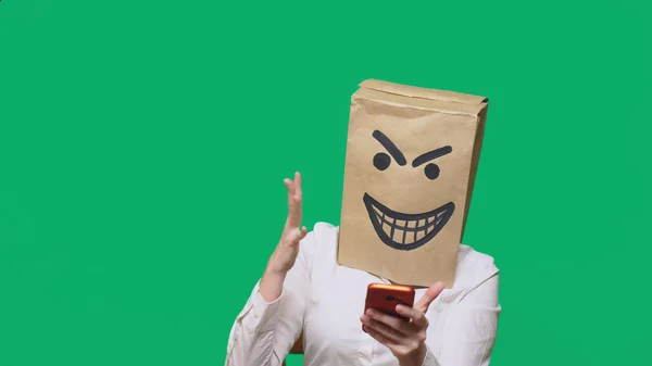 Koncepcja emocje, gesty. człowiek z pakietem na głowie, z pomalowane czarnym uśmiechniętą twarz, diabeł, podstępny, gloating, rozmowy na telefon komórkowy. — Zdjęcie stockowe