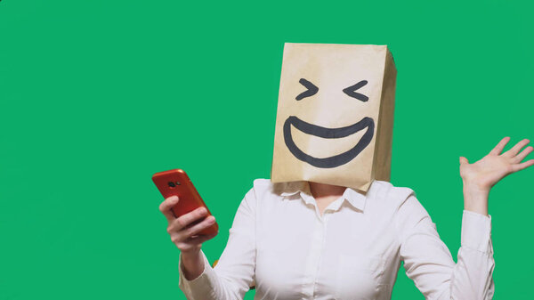 concept of emotions, gestures. a man with paper bags on his head, with a painted emoticon, smile, joy. talking on a cell phone.