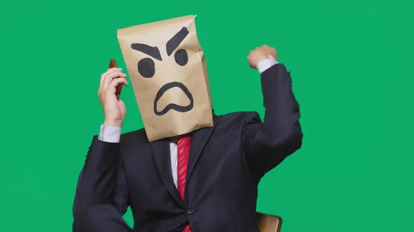Concept van emotie, gebaren. een man met een pakket op zijn hoofd, met een geschilderde smiley agressief en boos. praten op een mobiele telefoon — Stockfoto