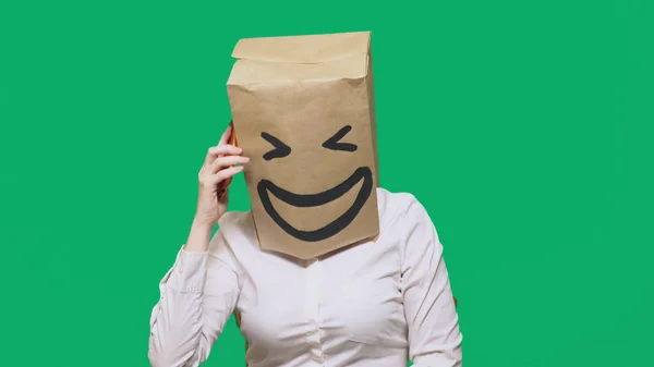 Концепция эмоций, жестов. человек с бумажными пакетами на голове, с раскрашенным смайликом, улыбкой, радостью. разговор по мобильному телефону — стоковое фото