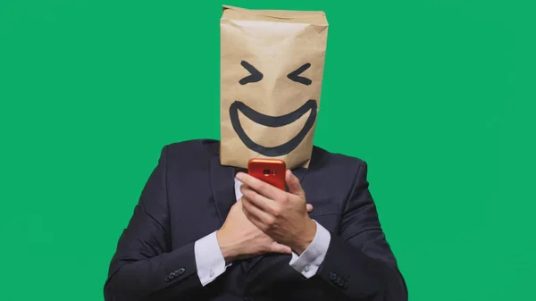 Concepto de emociones, gestos. un hombre con bolsas de papel en la cabeza, con un emoticono pintado, sonrisa, alegría. hablando por un teléfono celular — Foto de Stock