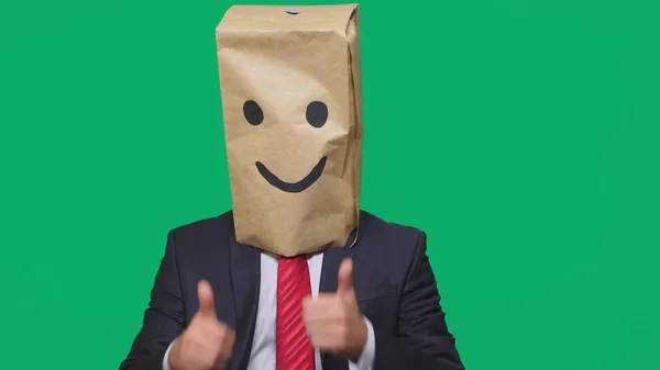 Concepto de emociones, gestos. un hombre con bolsas de papel en la cabeza, con un emoticono pintado, sonrisa, alegría — Foto de Stock