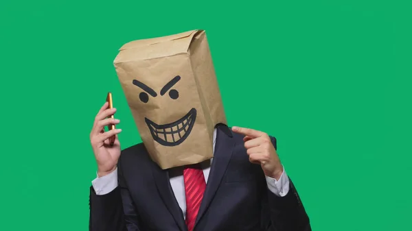 Begreppet känslor, gester. en man med ett paket på huvudet, med en målad svart smiley, en djävul, listig, göra, talar i en mobiltelefon. — Stockfoto