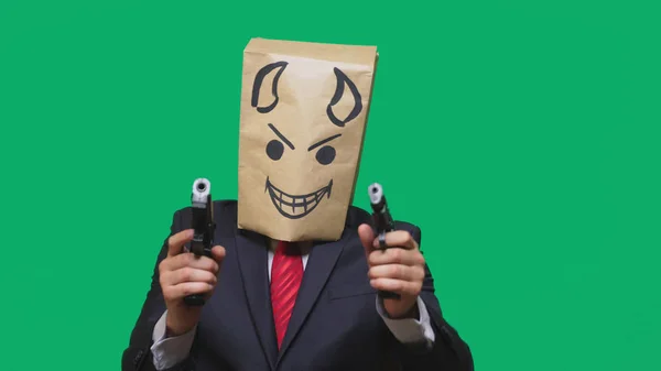 Concetto di emozione, gesti. un uomo con un pacco in testa, con un sorriso dipinto arrabbiato, furbo, gongolante, diavolo, pistole in mano — Foto Stock