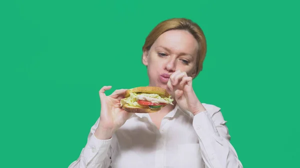 Geschäftsfrau beim Sandwich auf grünem Hintergrund. Konzept für schnelles Mittagessen. — Stockfoto