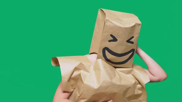 Conceito de emoções, gestos. um homem com sacos de papel na cabeça, com um emoticon pintado, sorriso, alegria — Fotografia de Stock