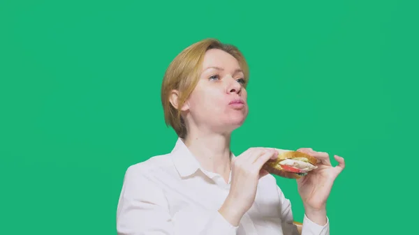 Zakenvrouw Eten Van Een Boterham Een Groene Achtergrond Snelle Lunch — Stockfoto