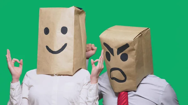 Pojęcie emocji i gesty. Dwie osoby w worki papierowe na głowę z malowane buźki. Przysięga, agresywne uśmiechniętą. Drugi uśmiechy na niego. — Zdjęcie stockowe
