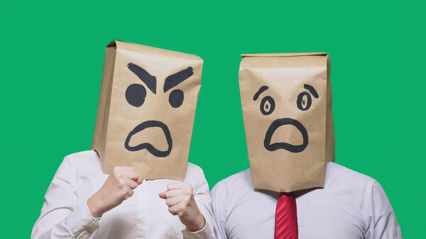 The concept of emotions and gestures. Two people in paper bags with smiles. Aggressive smiley swears. Second scared