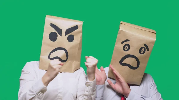 O conceito de emoções e gestos. Duas pessoas em sacos de papel com sorrisos. Um sorriso agressivo jura. Segundo assustado — Fotografia de Stock