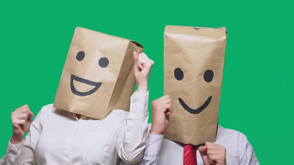 Αντίληψη των συναισθημάτων, χειρονομίες. ένα ζευγάρι των ανθρώπων με σακούλες στο κεφάλι τους, με ζωγραφισμένα φατσούλα, χαμόγελο, χαρά, γέλιο. — Φωτογραφία Αρχείου