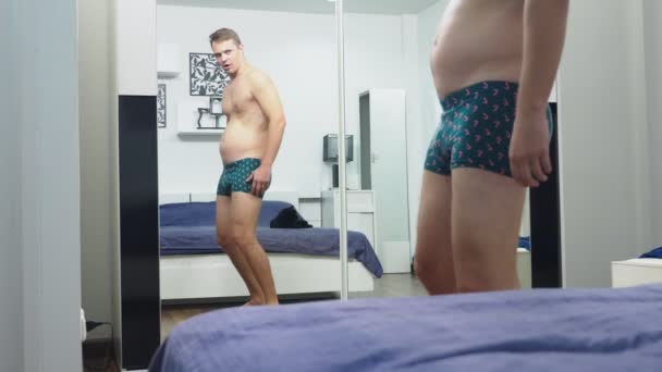 若い男が彼の寝室の鏡の前の筋肉をチェック — ストック動画