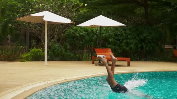 Jovem e alegre homem bonito pulando na piscina, de férias no hotel. férias de verão conceito de viagem — Vídeo de Stock