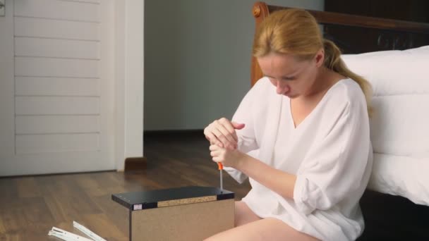 Assemblage de meubles à la maison, une femme au foyer assemble un bureau d'ordinateur à l'aide d'outils à main . — Video