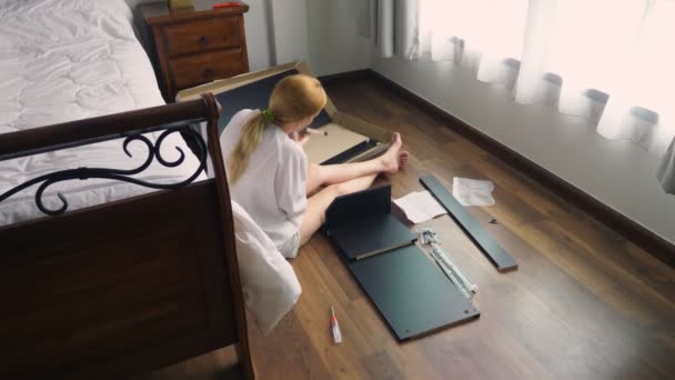 Assembling furniture at home, a housewife assembles a computer desk using hand tools. — Stock Video