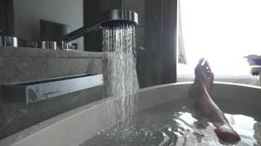 bacaklar otelin tuvaletinde mans. sıcak su banyosu dökülen ve buhar geliyor.