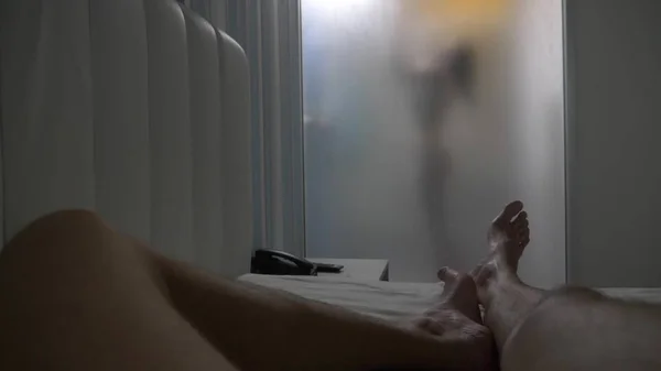 Mulher atrás de vidro desfocado. Menina se preparando tomar banho. Uma mulher na casa de banho. um homem observa como uma mulher toma um banho através de uma parede de vidro no chuveiro . — Fotografia de Stock