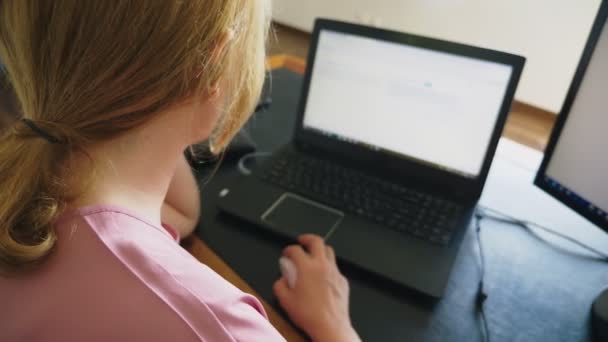 美丽的年轻女子在笔记本电脑和电脑上工作, 而坐在办公桌前. — 图库视频影像
