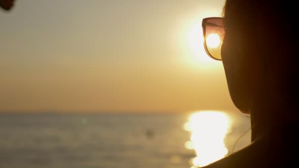 Hermoso atardecer soleado en el mar. vista a través de gafas de sol. mujer en gafas de sol mira la puesta de sol en el mar — Vídeo de stock