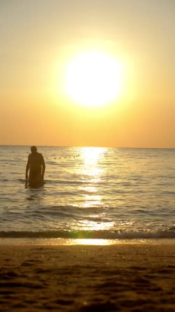 Красивий захід сонця на морі. літні люди ходять уздовж узбережжя ввечері — стокове відео