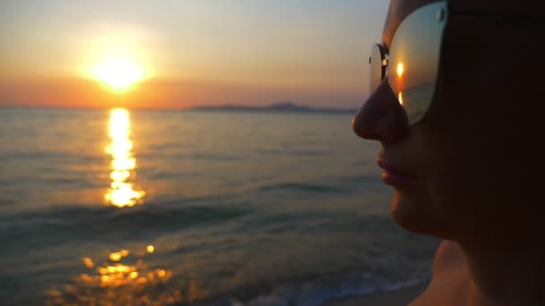 Krásný slunný západ slunce na moři. Zobrazit přes sluneční brýle. Žena v sluneční brýle se dívá na západ slunce na moři — Stock video