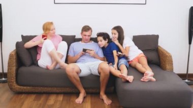 Büyüleyici aile, Anne, Baba, kızı ve oğlu oturma odasında birlikte Tv izliyor musun, herkes onun telefona bakıyor