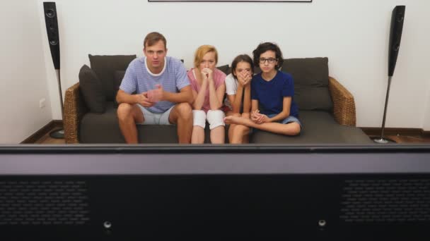 Charmante famille, maman, papa, fille et fils regardent ensemble la télévision dans le salon — Video
