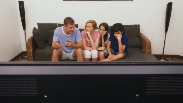 Charmante famille, maman, papa, fille et fils regardent ensemble la télévision dans le salon — Video