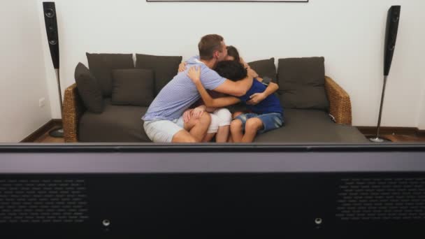 Charmiga familj, Mamma, Pappa, dotter och son tittar på Tv i vardagsrummet tillsammans — Stockvideo