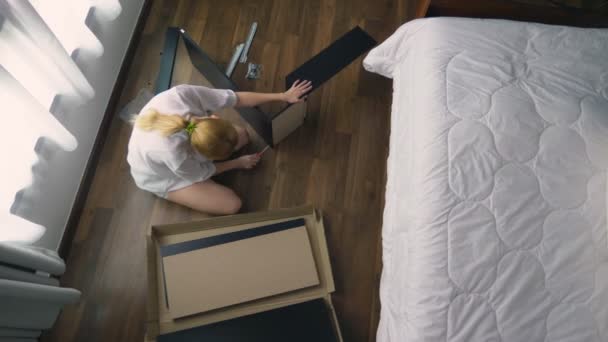 Assemblage de meubles à la maison, une femme au foyer assemble un bureau d'ordinateur à l'aide d'outils à main . — Video