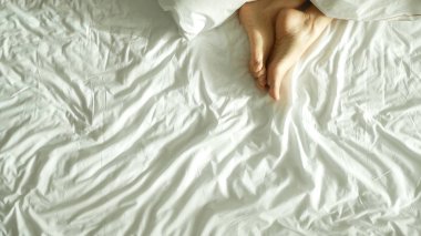 Yukarıda, beyaz yatak yatak görünümünde kadın bacakları