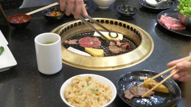 Korece Barbekü ızgara. aşçı insanlar ve bir restoranda Kore bir ızgarada pişmiş yemekler yiyin. yakın çekim.