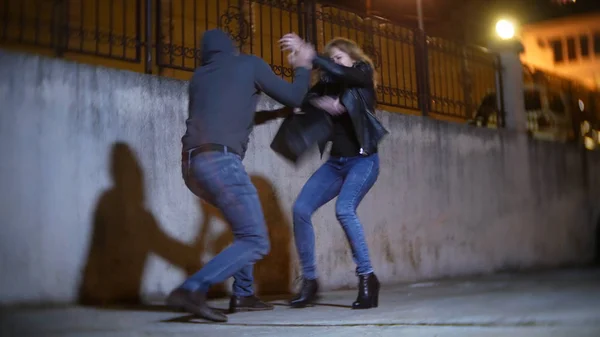 A male robber, threatens a woman and takes her purse, in a dark alley. at night — Stock Photo, Image