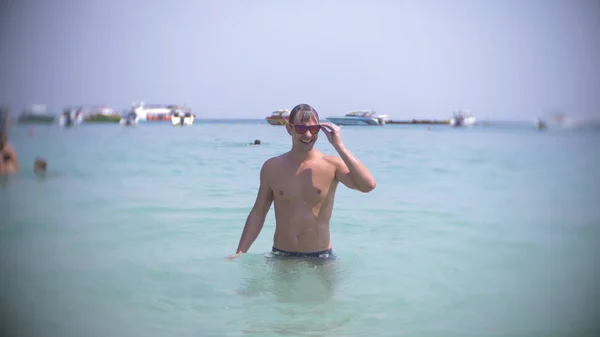 Un jeune homme plonge dans la mer portant des lunettes de soleil. émerge et sourit — Photo