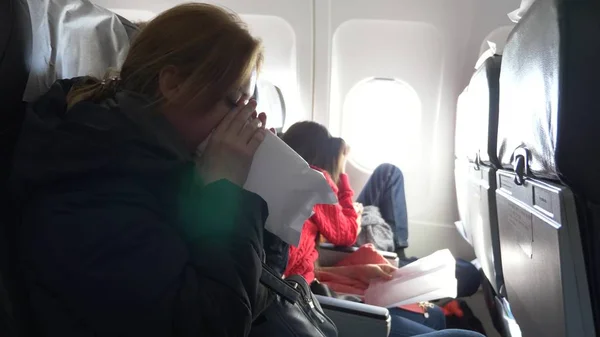 Vrouw in een vliegtuig met kinderen op een patrijspoort achtergrond. het vliegtuig ging de zone van turbulentie. het meisje begon paniek, ze ademt in een papieren zak. — Stockfoto