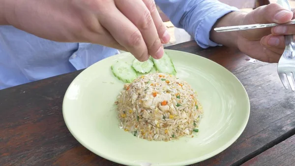 Närbild. man pressar limejuice på en maträtt med rör stekt ris med ägg och räkor, dekorerad med gurka. — Stockfoto