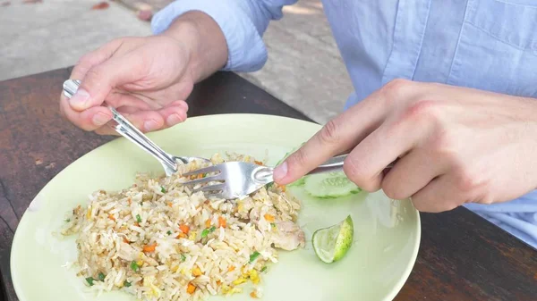 Närbild. man pressar limejuice på en maträtt med rör stekt ris med ägg och räkor, dekorerad med gurka. — Stockfoto